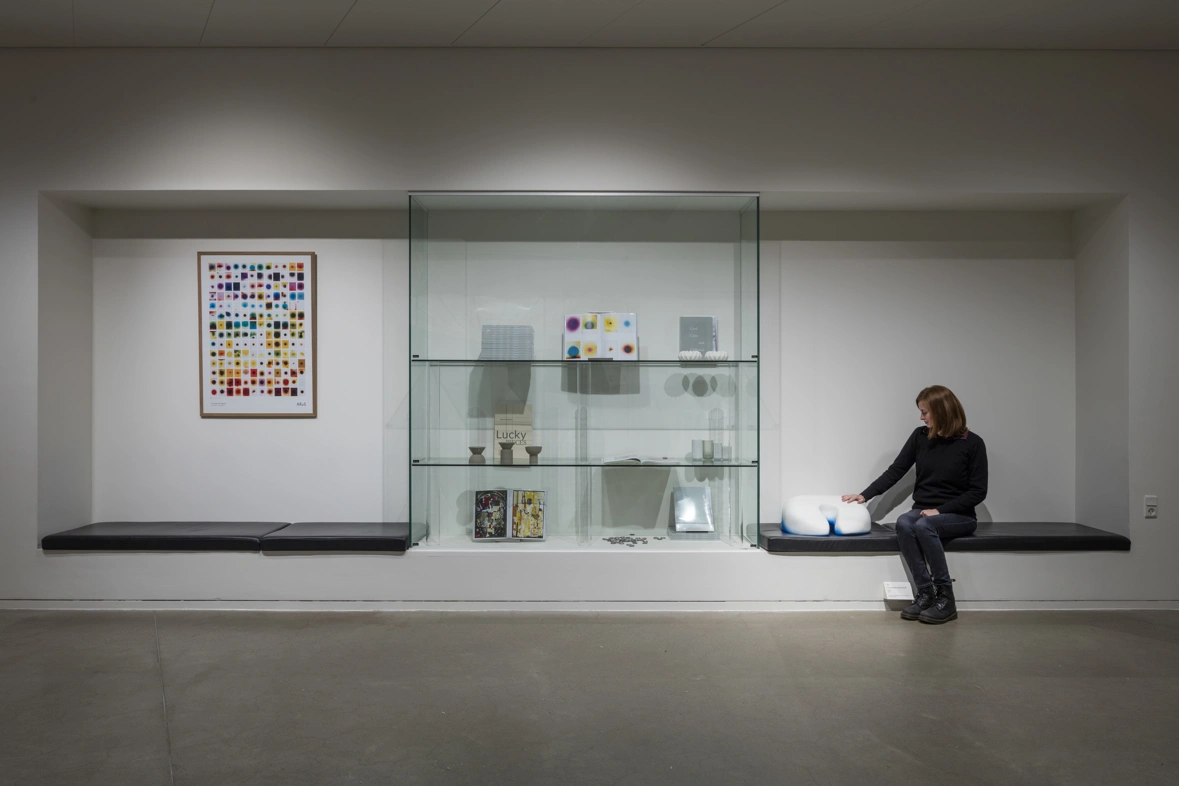 kvinde på bænk i udstilling ved siden af kunst